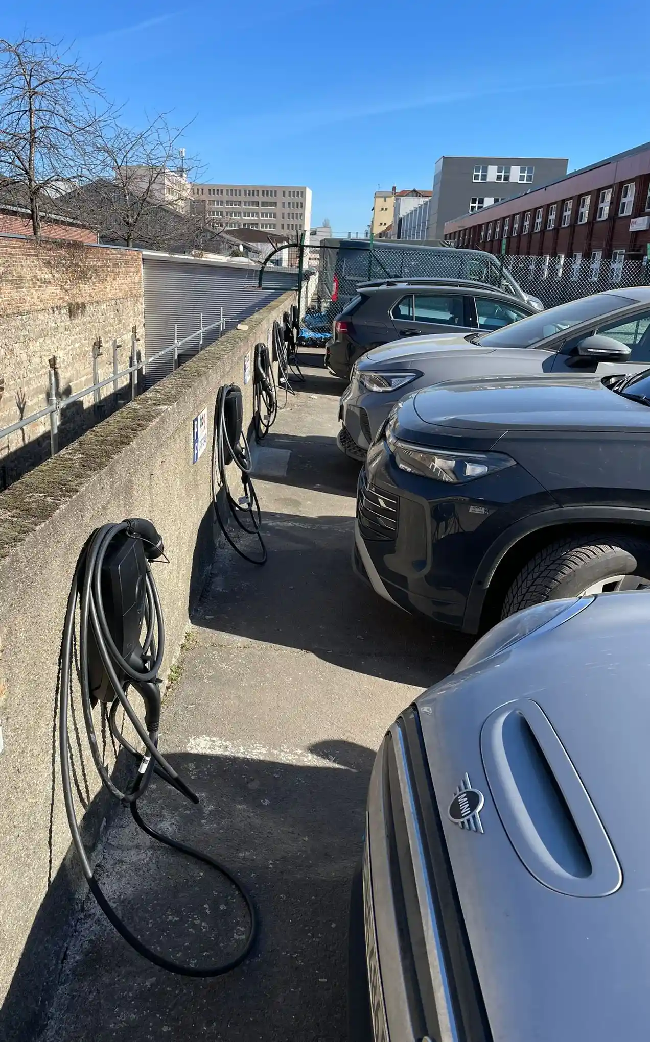 Elektroautos laden an Wallboxen entlang der Stellplätze einer Baugenossenschaft in Berlin