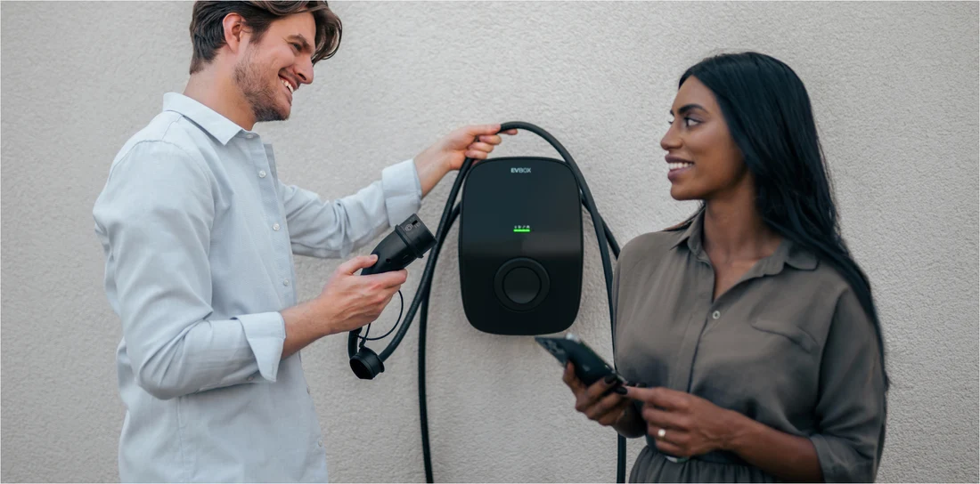 Zwei Personen halten eine EVBox Livo Wallbox vor einer hellen Wand